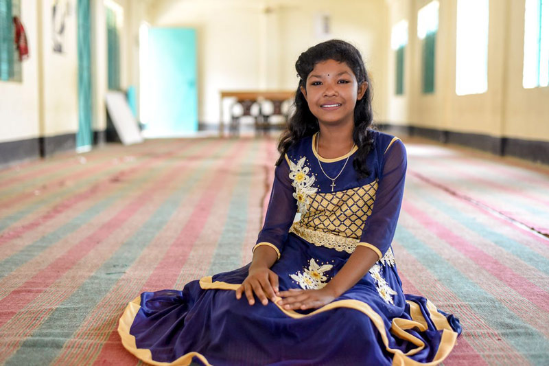 A girl smiles while sitting on the floor of her child development center