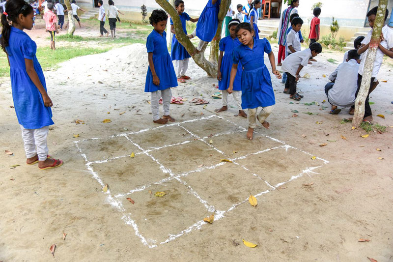 A group of children play a traditional game outside their child development center