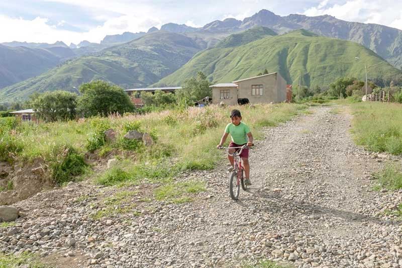 A boy rides a bicycle down a rocky path in Bolivia