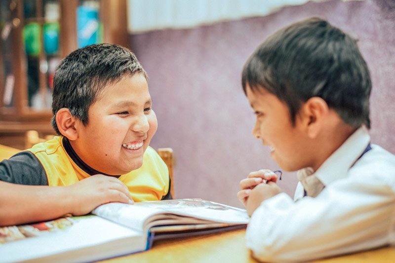 Two boys laugh and read the Bible together