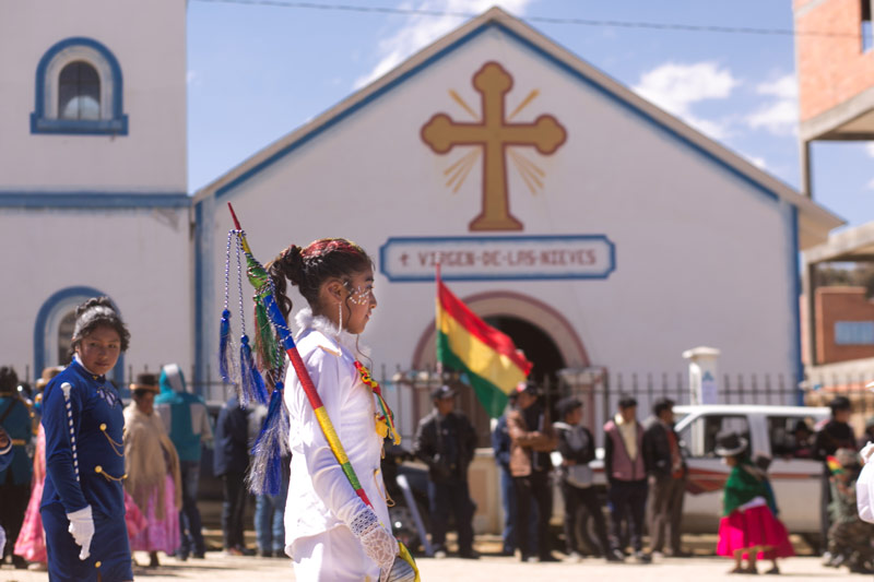 A girl walks as part of a parade in front of a church