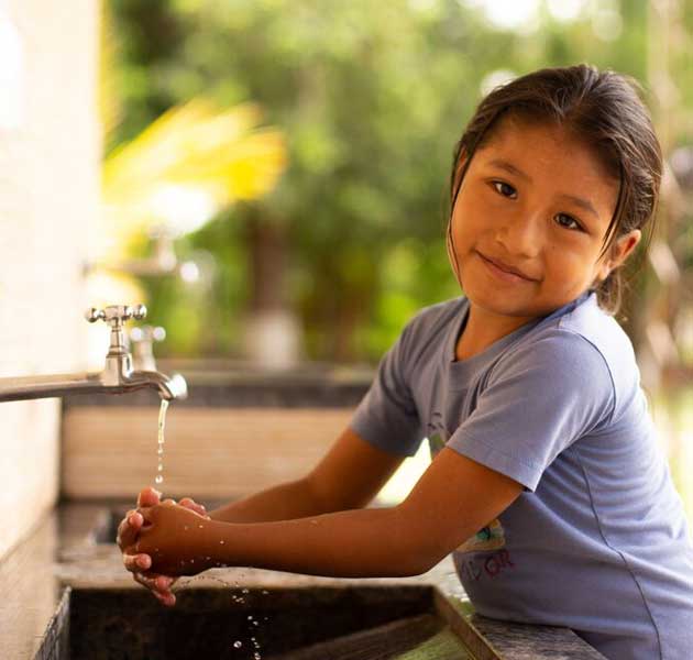 A girl cleaning her hands with safe water provided by the Compassion center