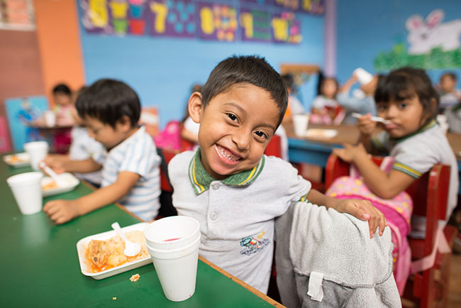 Boy smiling while eating lunch at school