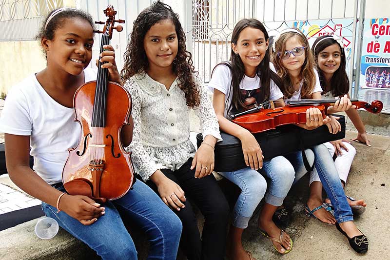 A group of girls hold musical instruments at their child development center