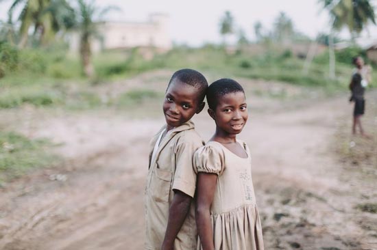 A boy and girl standing back to back smiling