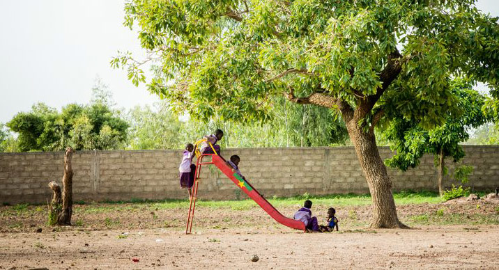 Children play on a slide outside their child development center