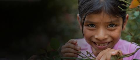 A young girl smiling while picking flowers