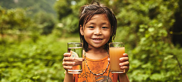 A girl holding a glass of dirty water and a glass of clean water