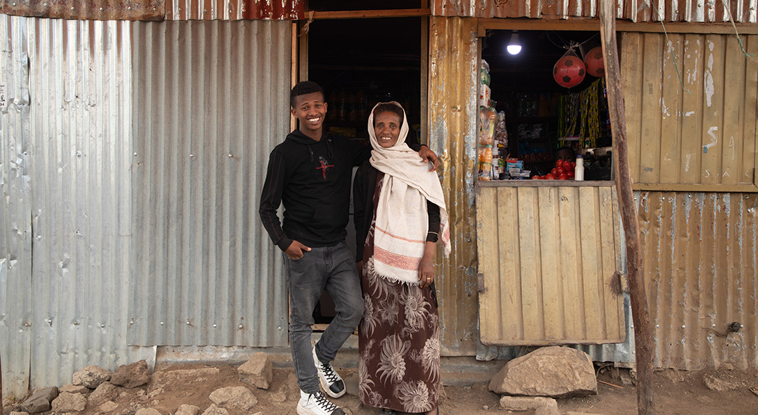 Mikiyas stands outside his shop with his mother