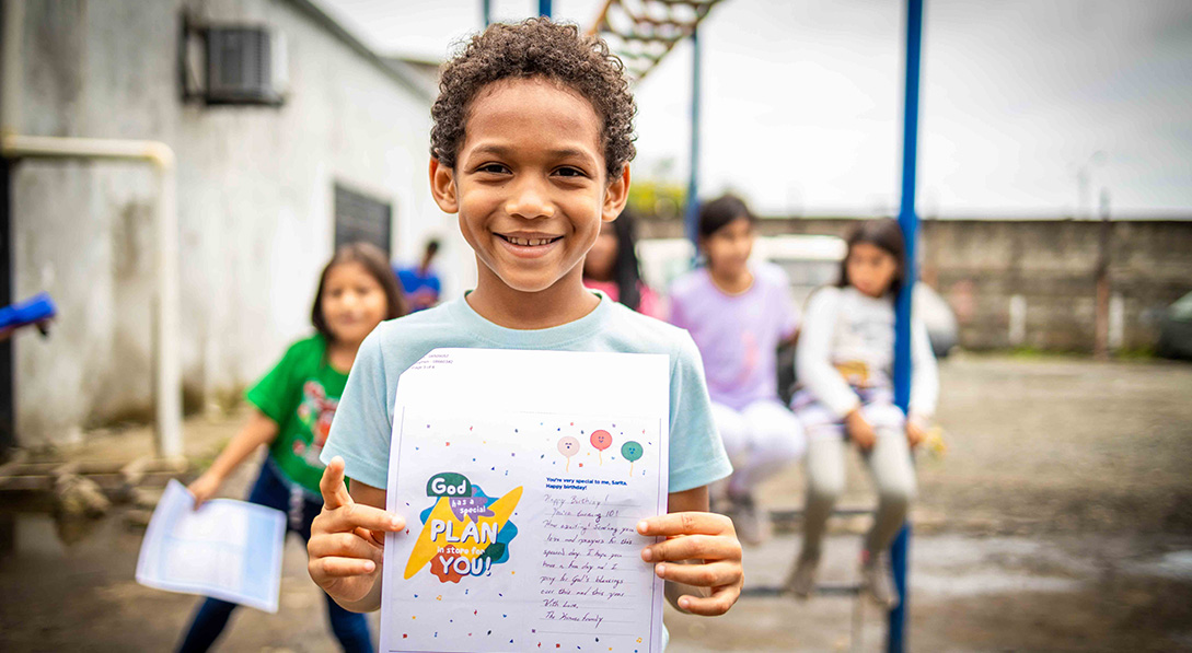 Boy smiling and holding letter.