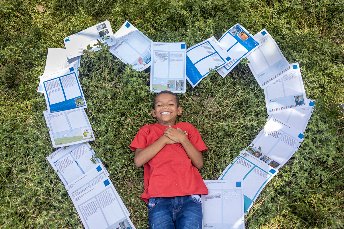 boy smiles and lies on letters shaped as a heart
