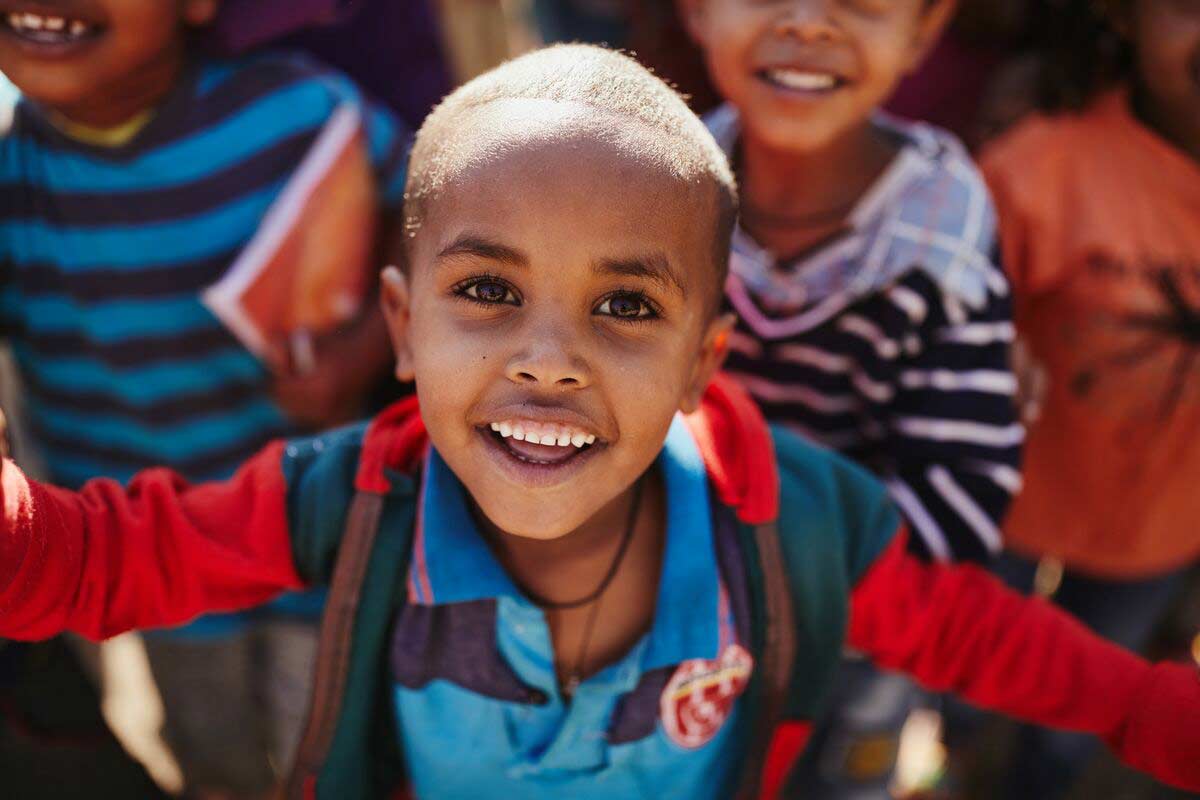 An Ethiopian boy stretching our his arms and smiling
