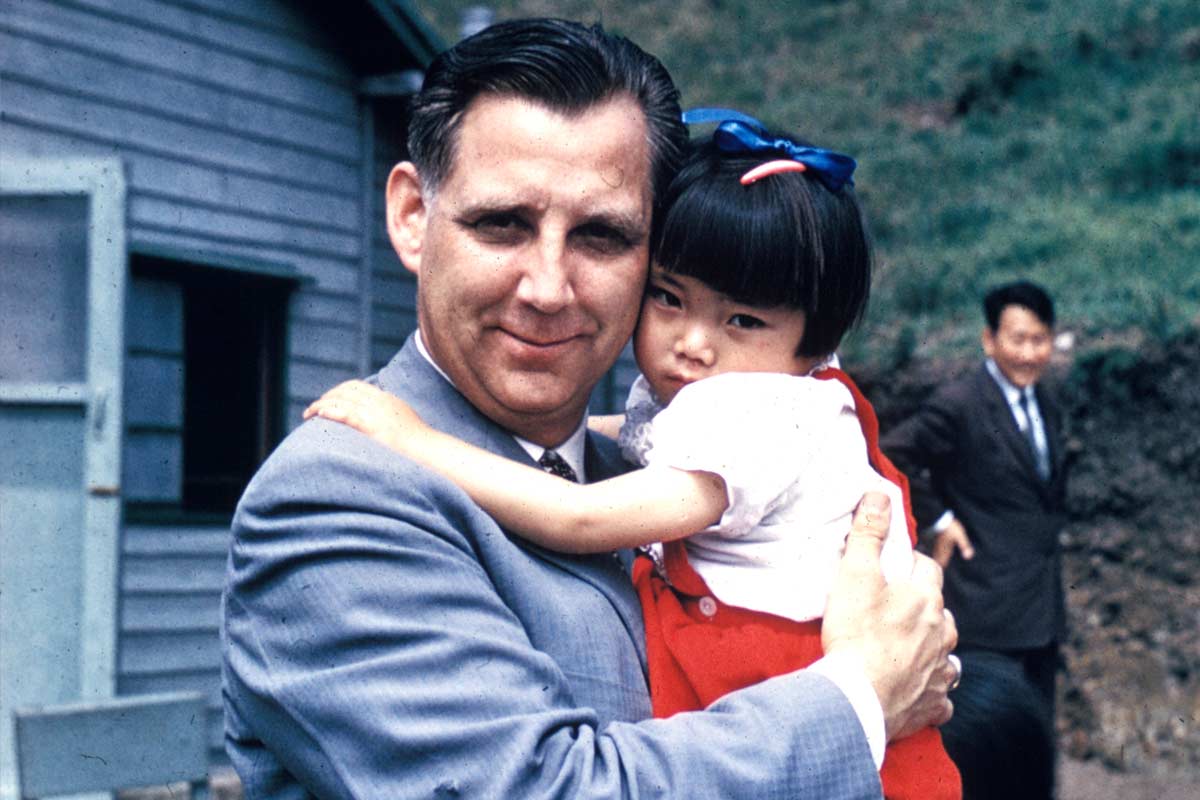 Reverend Everett Swanson holding a young girl in South Korea