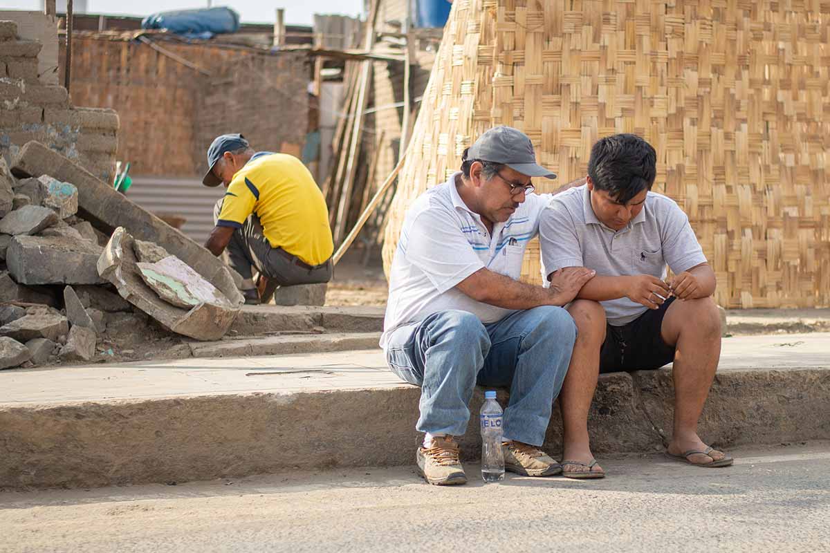 A disaster relief volunteer sits and prays with a young man affected by the event