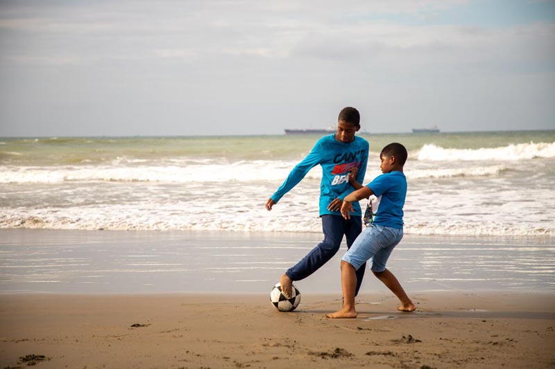 Boys play soccer on the beach