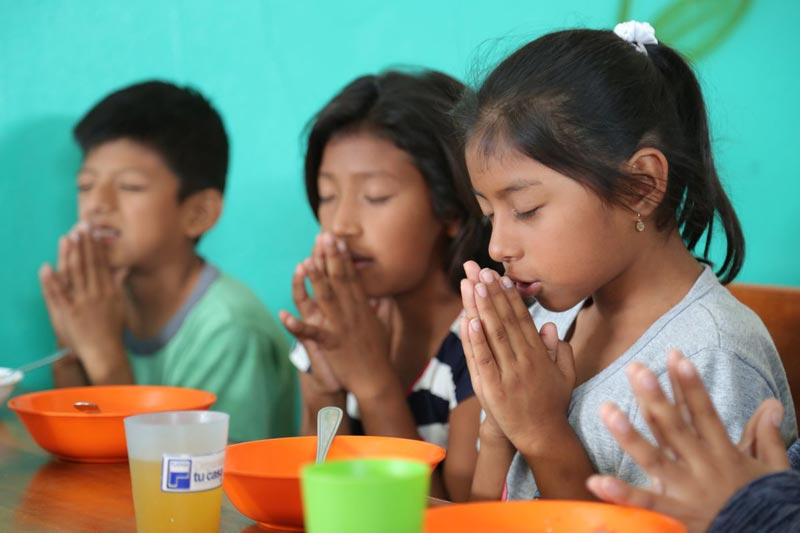 Children pray before their meal