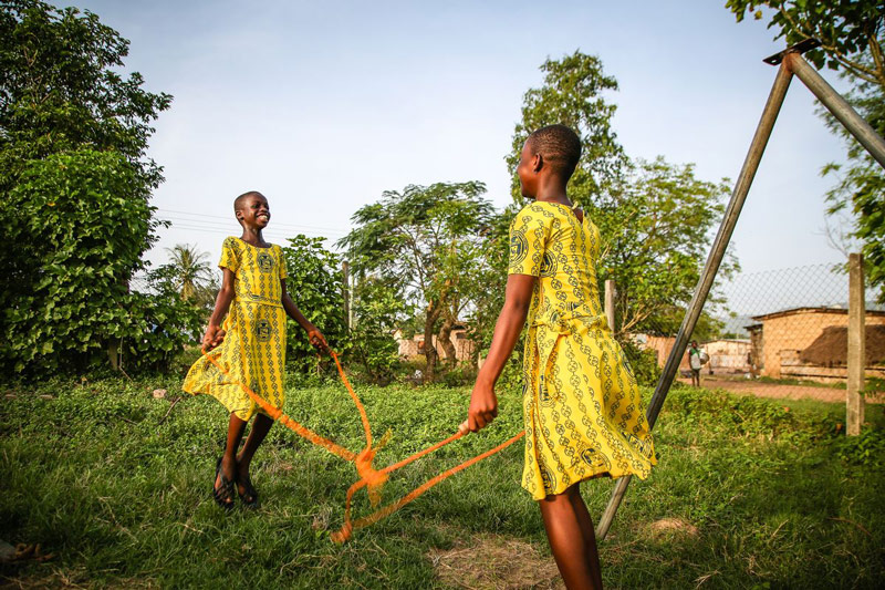 Two smiling girls play a game while holding a rope