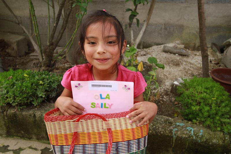 A young girl holds a letter from her sponsor
