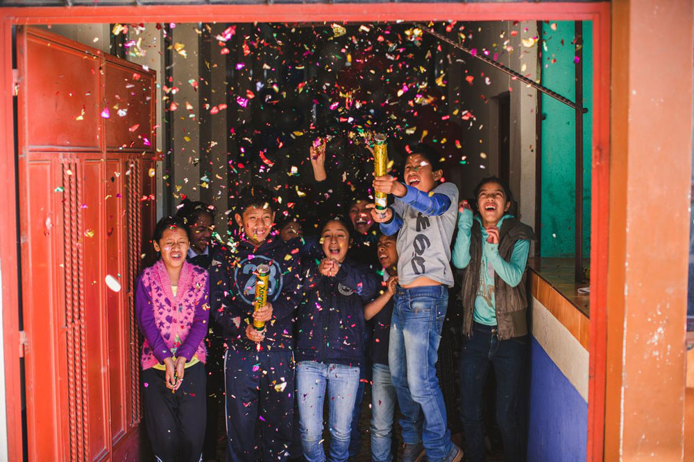 A group of children celebrate the New Year by shooting confetti into the air