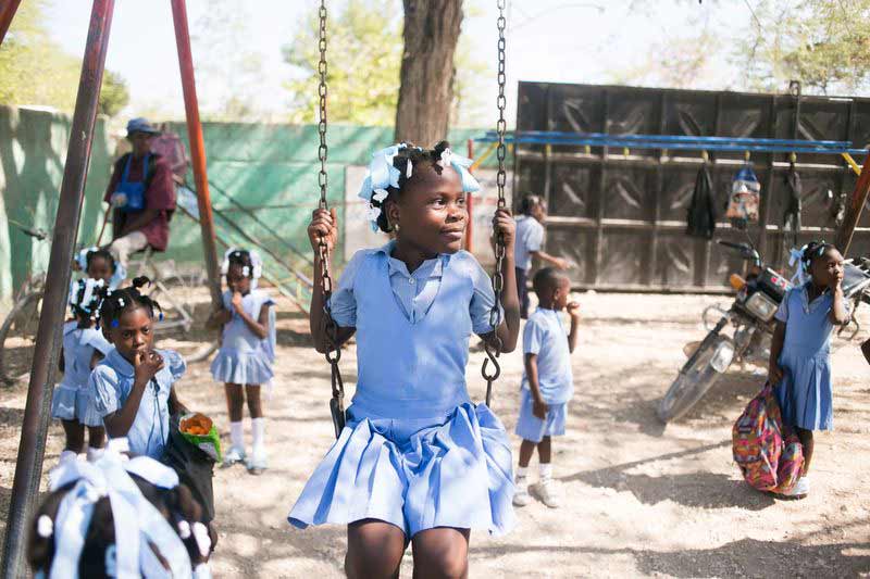 A young girl swings on the playground at her child development center