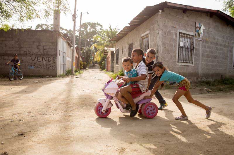 A group of children play together with a toy bicycle