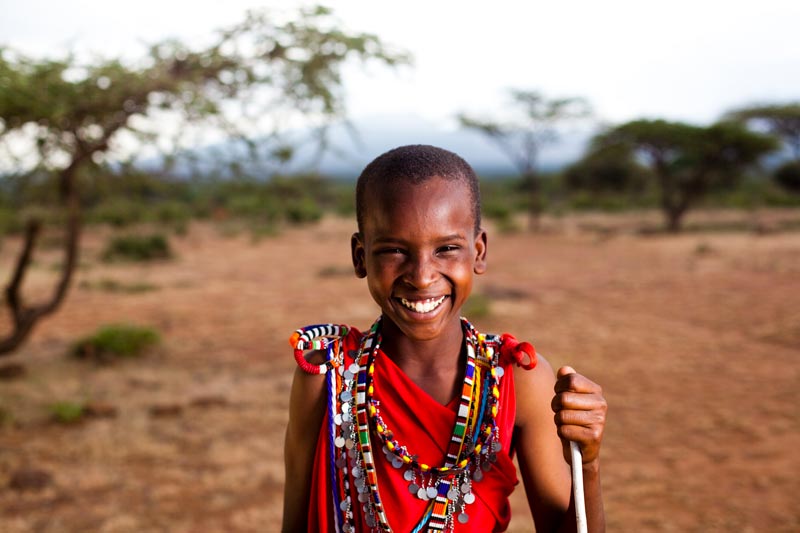 A young Masai boy smiles in the desert landscape of Kenya