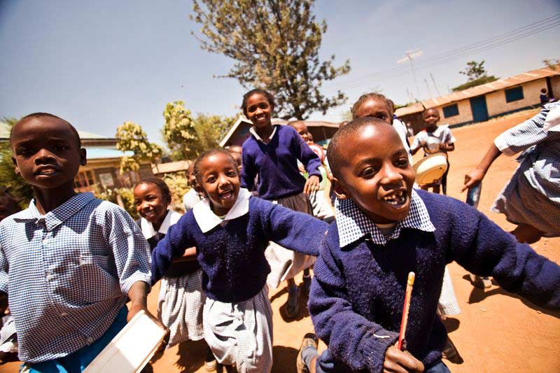 A group of children smile and run at their child development center