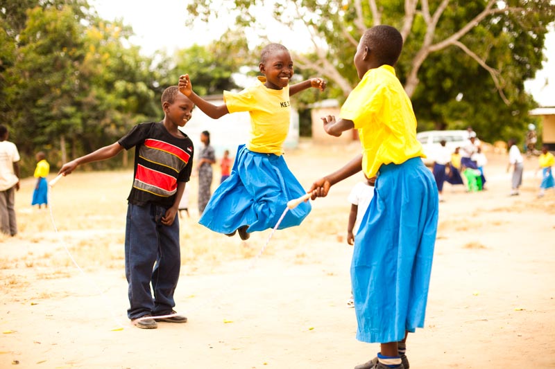 Children smile while playing jump rope at their child development center playground