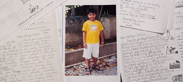 A picture of a sponsored child among several letters written to the child