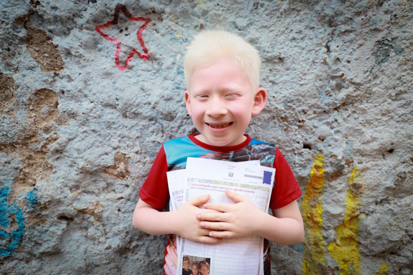 A boy smiles and holds a letter