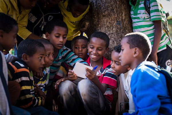A group of boys smiles and reads a letter