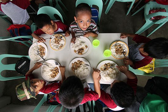 Children sitting around a table eating their meal at school