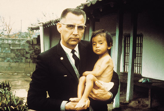 Rev. Everett Swanson holding a Korean orphan