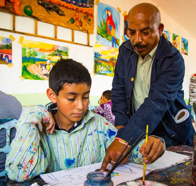 A teacher helping a boy with his art project