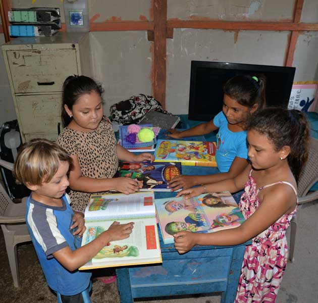 Children reading books at a blue desk in their classroom