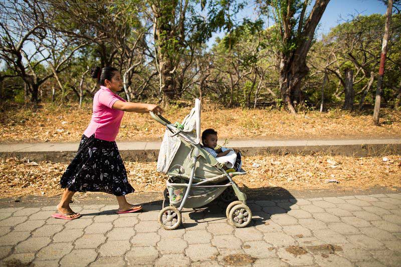 A mother pushes her baby in a stroller