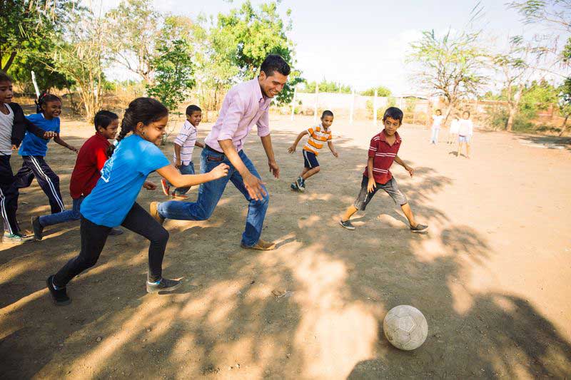 The local pastor plays soccer with children at the child development center
