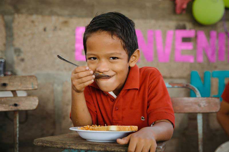 A young boy smiles as he enjoys a nutritious meal