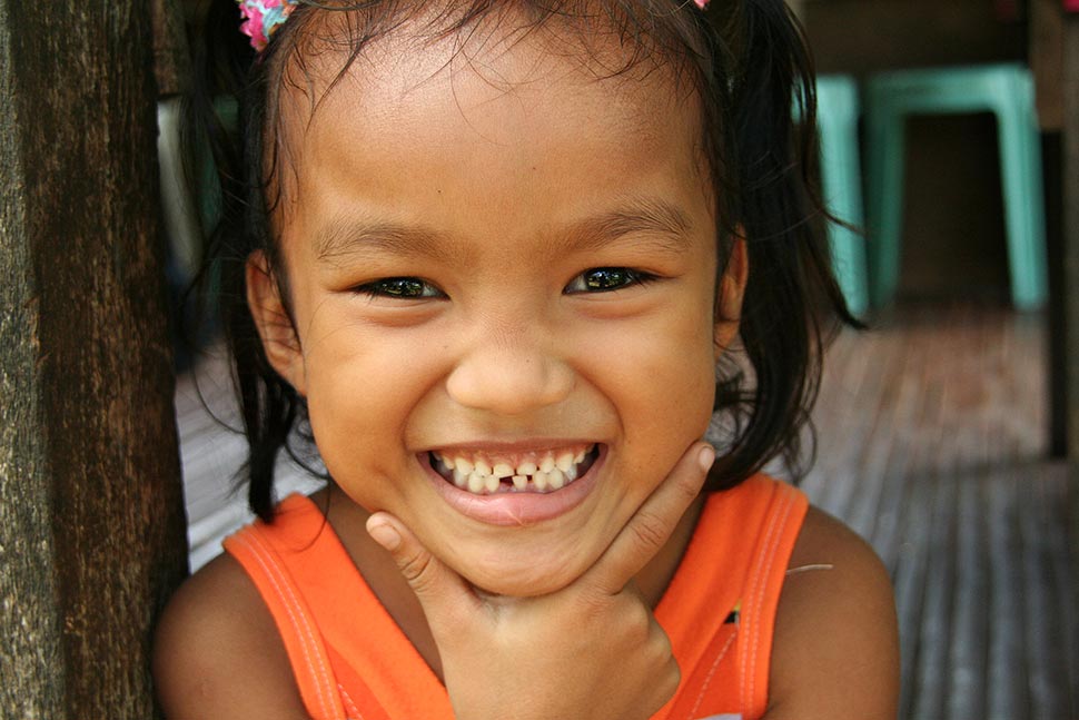 A smiling young girl in an orange tanktop