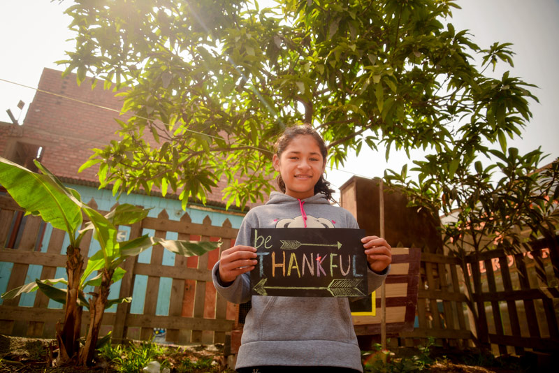A young lady holds up a sign saying "Thankful"