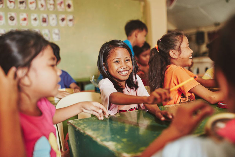 Children smile, laugh and play together in a classroom at their child development center