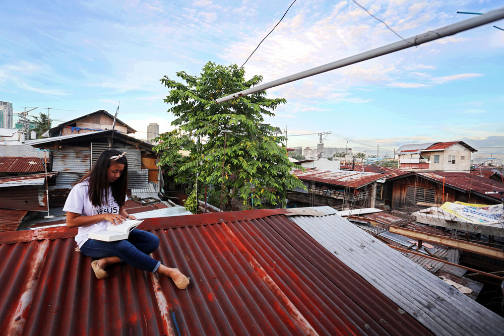 A girl sits on a rooftop reading