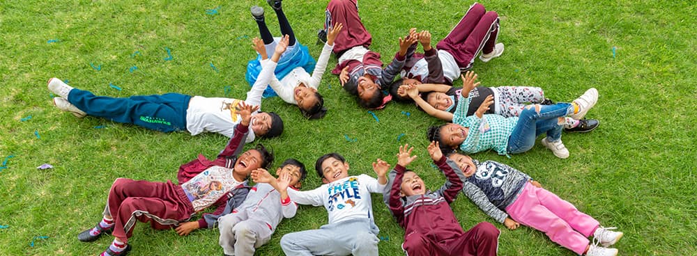 Many children laying on the ground in a circle laughing.