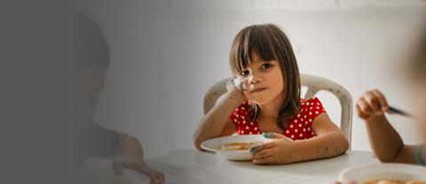 A girl sits at a table for a meal