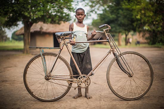 A girl stands behind a bicycle