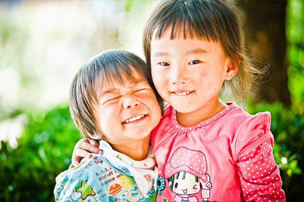 Two young girls embrace and smile