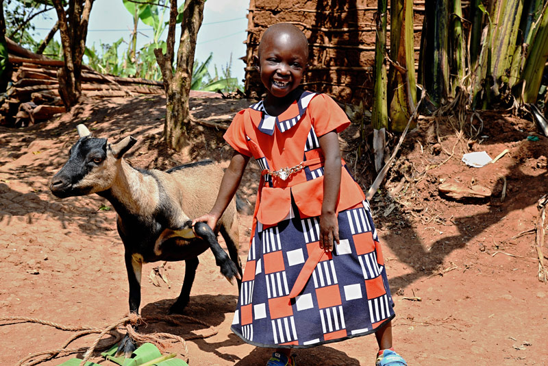 A girl smiles with a goat