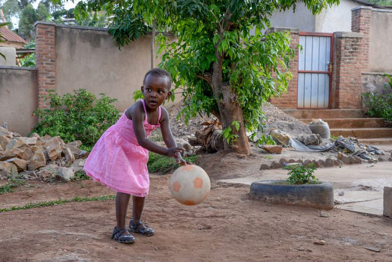 A girl plays with a soccer ball outside her home