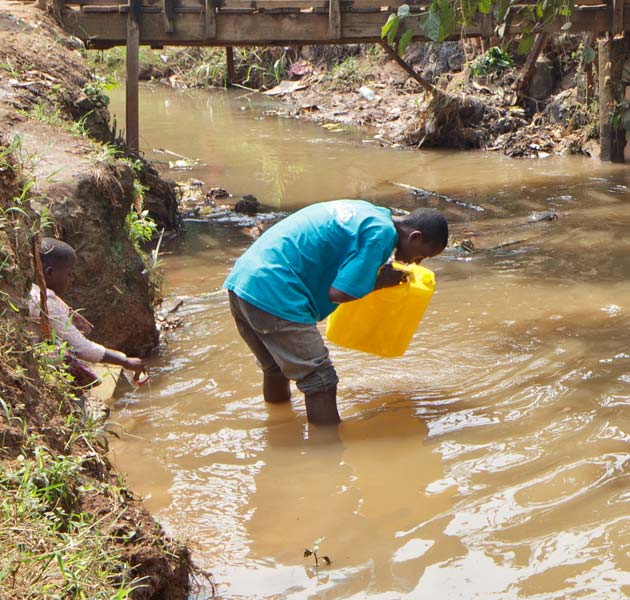 A boy filling his water jug from a local river