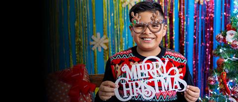 a boy holds a Merry Christmas sign